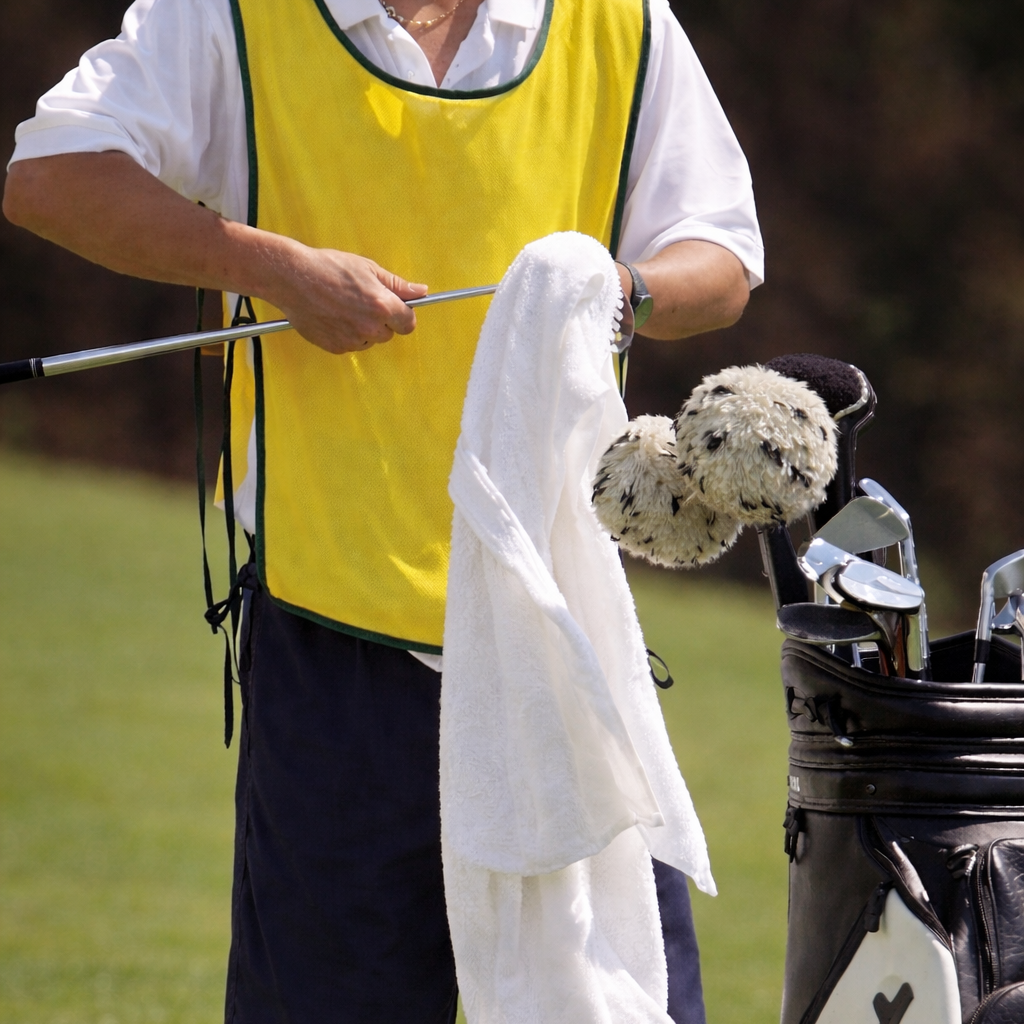 Person holding a golf club and towel on a golf course